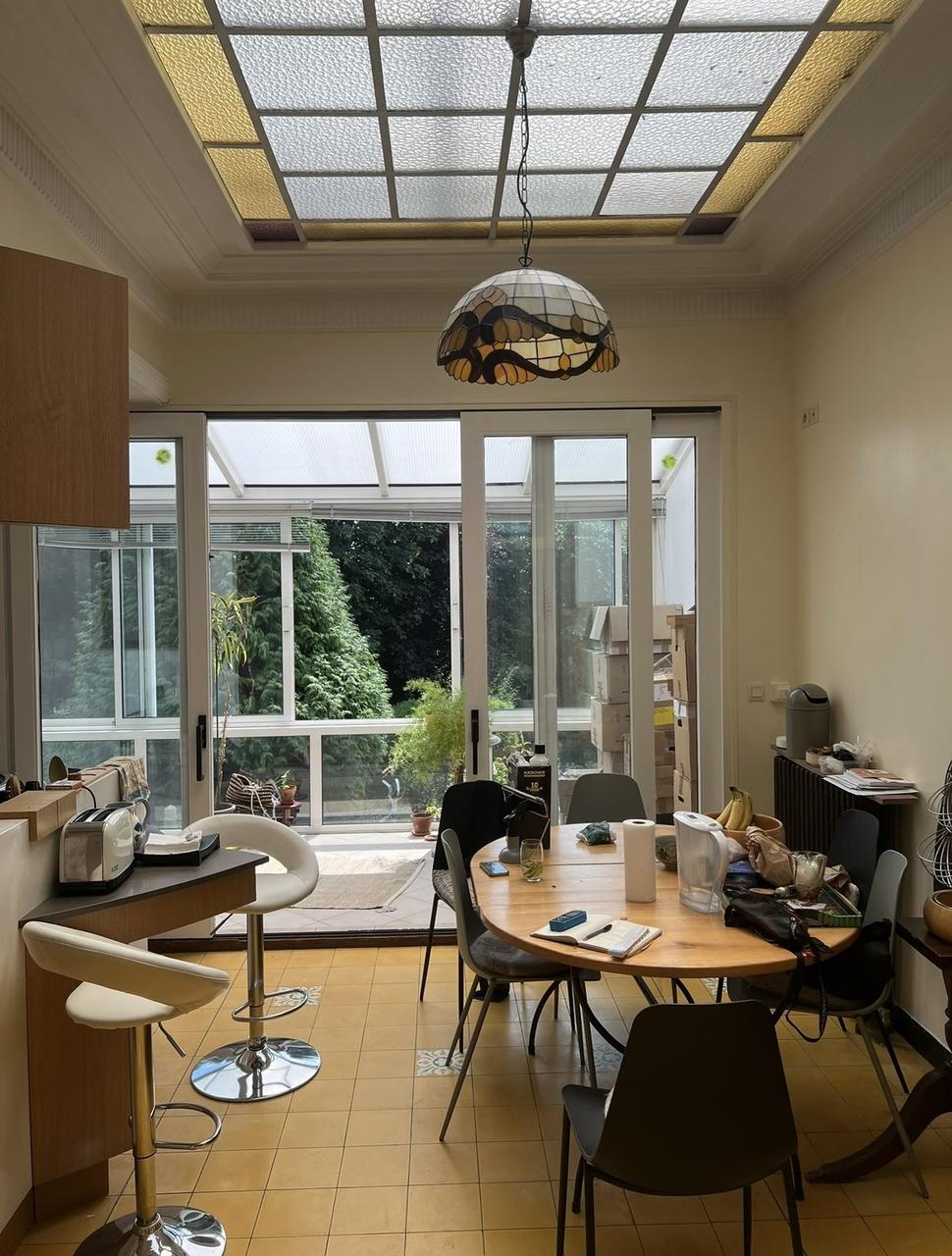 Cuisine avant – carrelage moutarde, table ronde, verrière jardin