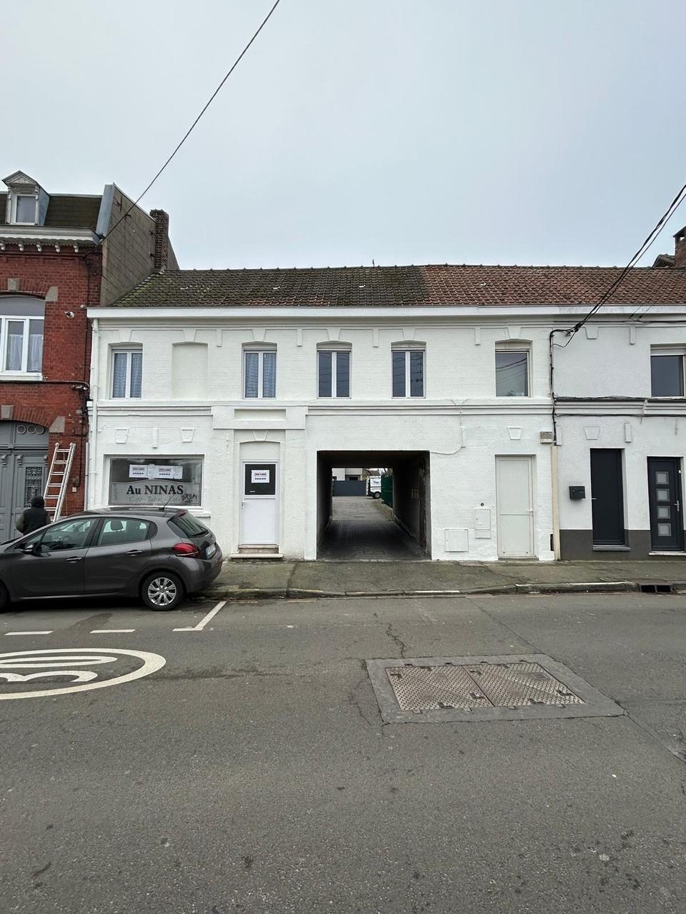Ravalement façade immeuble – peinture blanche sur local commercial avec passage voûté